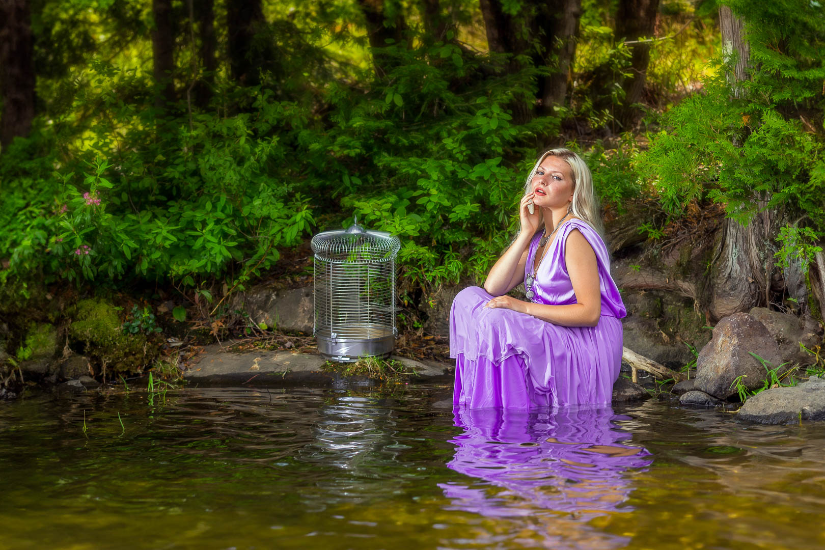Portrait de femme en robe mauve assise dans l'eau en extérieur, éclairée avec un flash cobra en fill light sous lumière naturelle