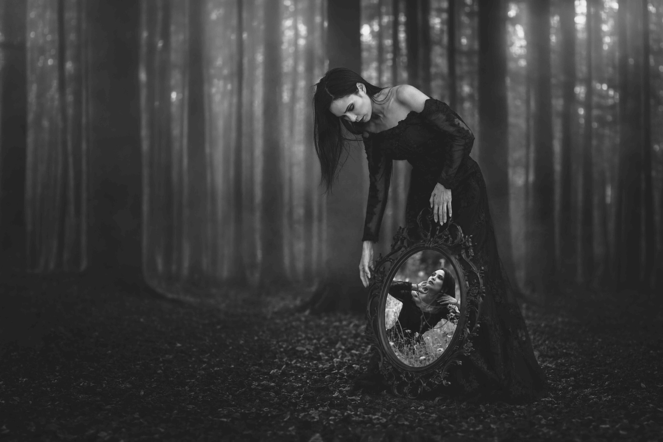 Sophie penchée vers un miroir ancien dans une forêt embrumée, cadrage large