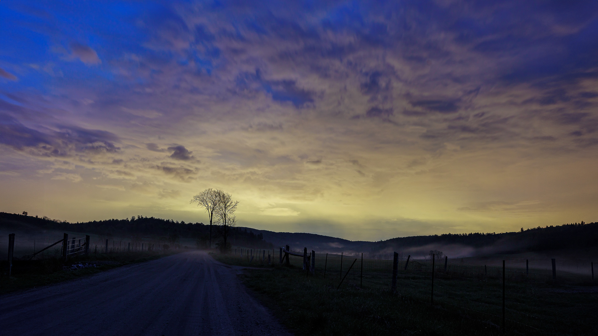 Route de campagne de nuit avec halo lumineux urbain visible au loin