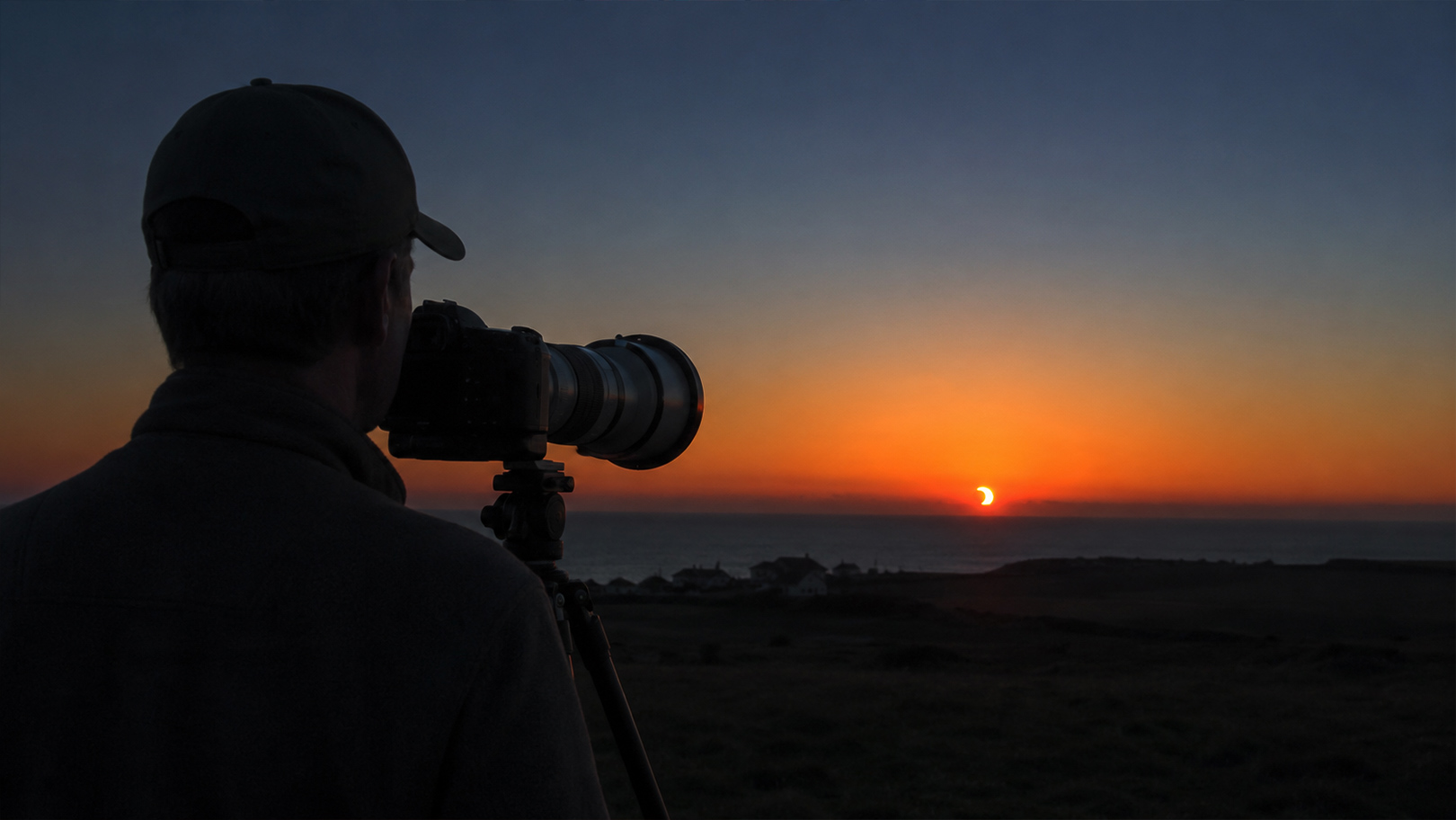 Photographe installé en fin de journée pour capturer l'éclipse solaire près de l'horizon en France