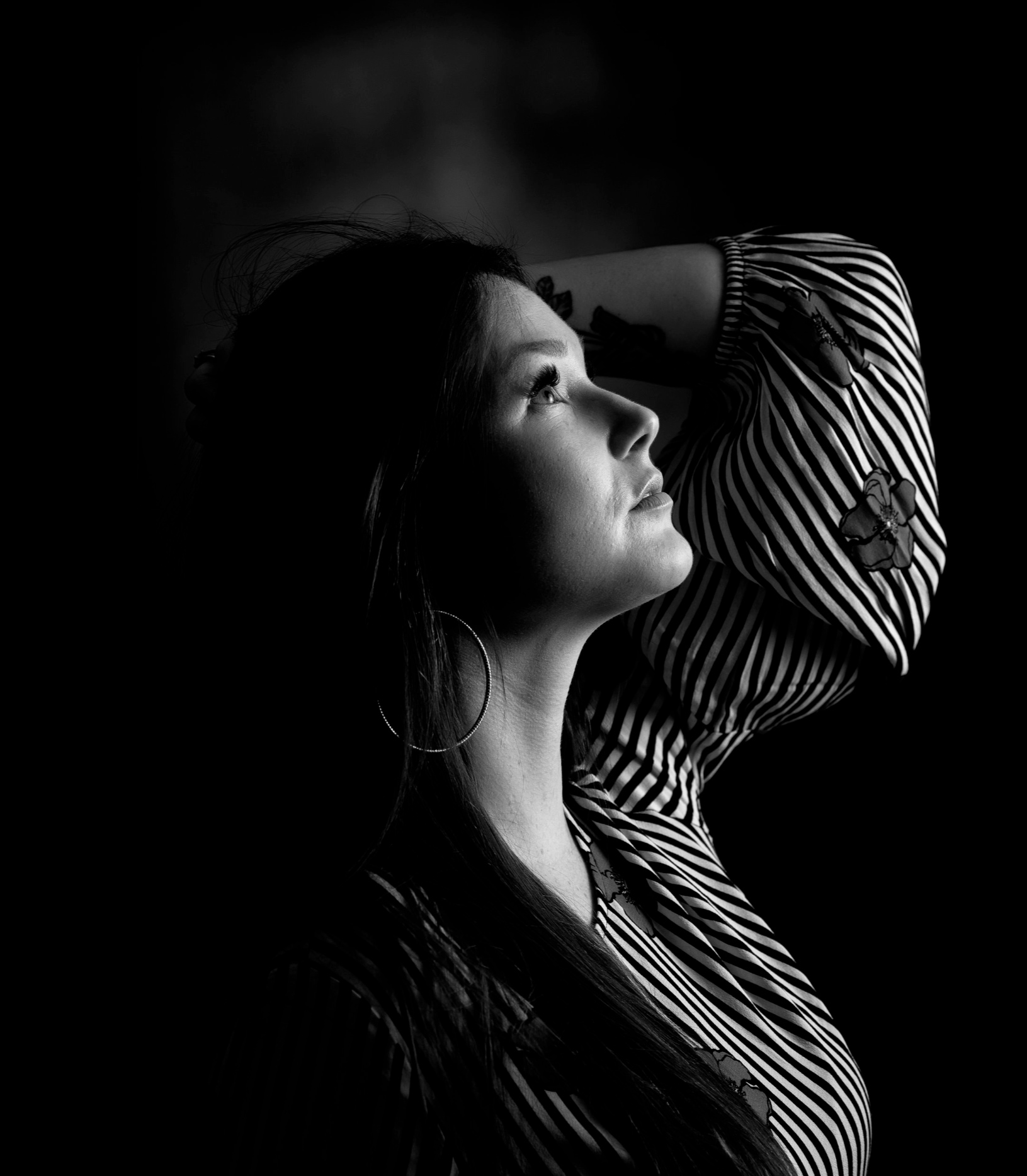 Portrait noir et blanc en studio, éclairage flash latéral directionnel, fond noir, modèle de profil regardant vers le haut
