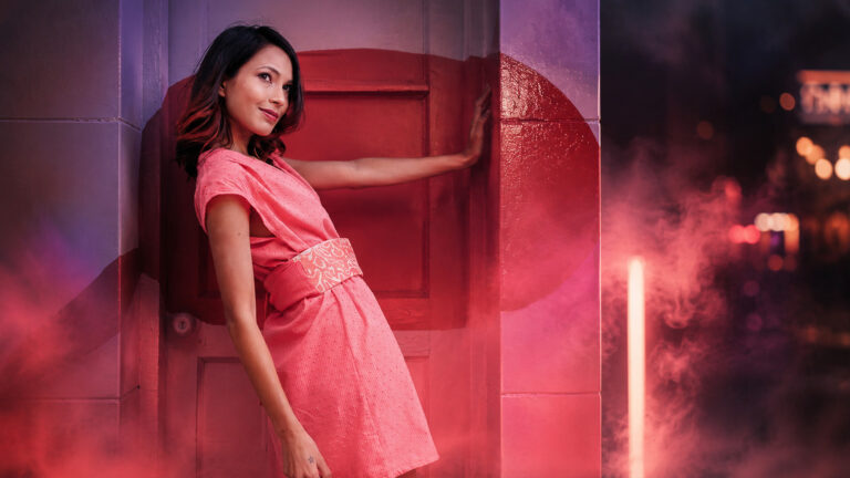 Portrait nocturne de femme en robe rose entourée de fumée rouge éclairée, tube LED visible en arrière-plan, lumières créatives en photographie