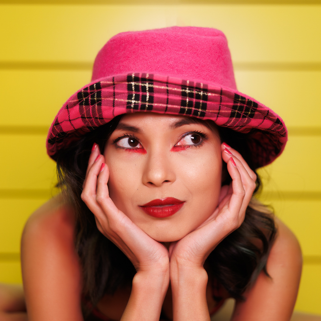 Portrait de studio réalisé avec panneaux LED, modèle avec chapeau rose sur fond jaune, sélectionné en concours de portrait