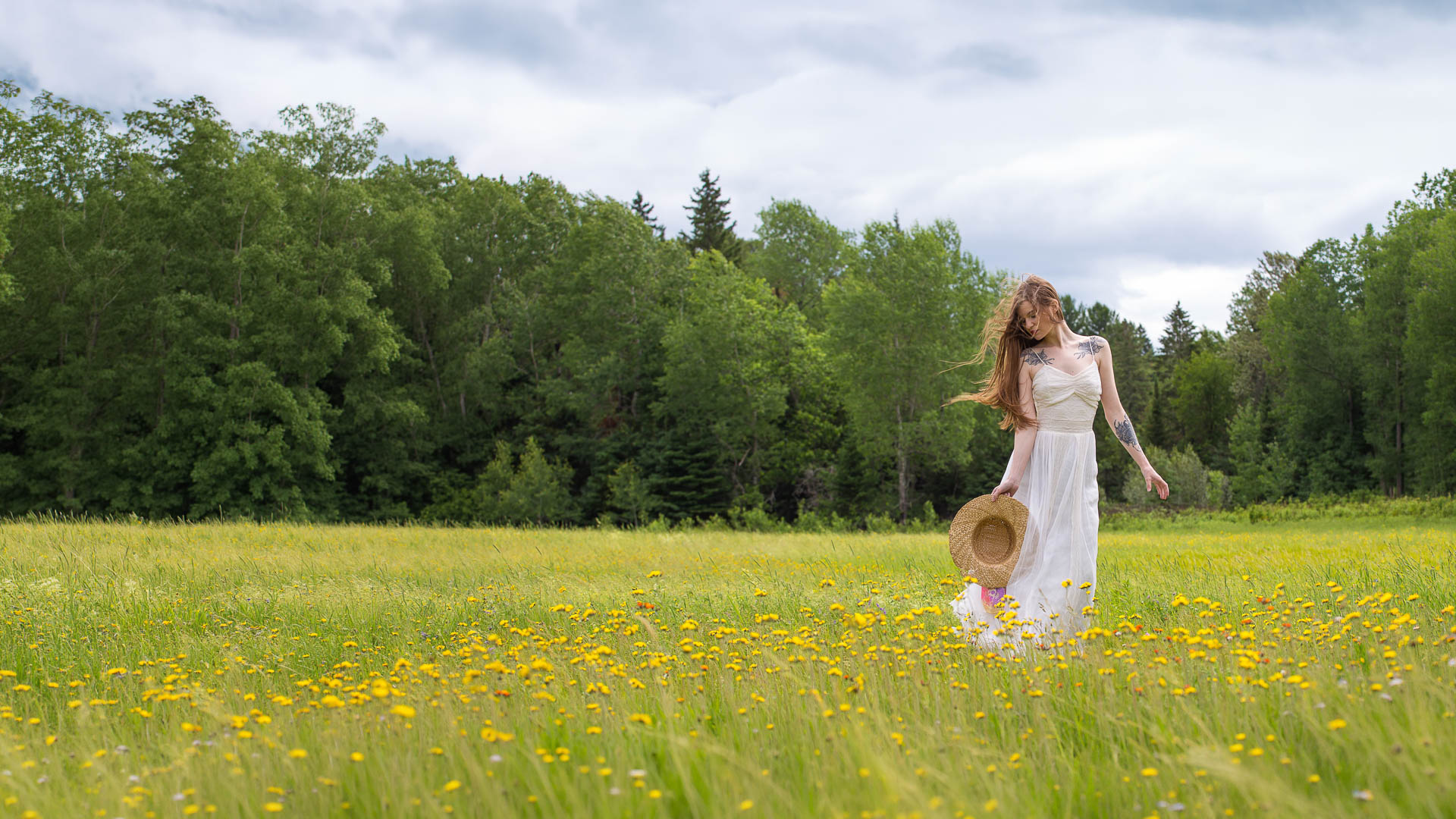 Portrait de femme en robe blanche dans un champ de fleurs sauvages, lumière douce et enveloppante produite par softbox et parapluie, cheveux dans le vent